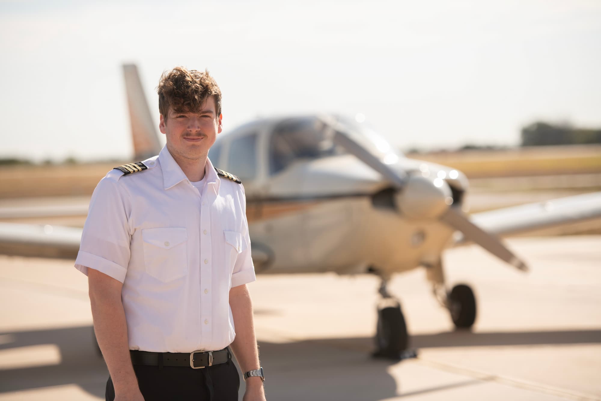 Student pilot standing in front of plane.