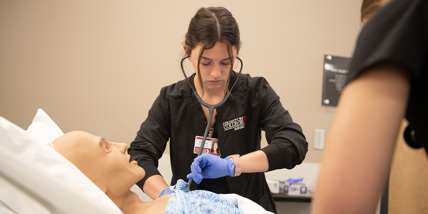 Nursing student works on dummy in lab.