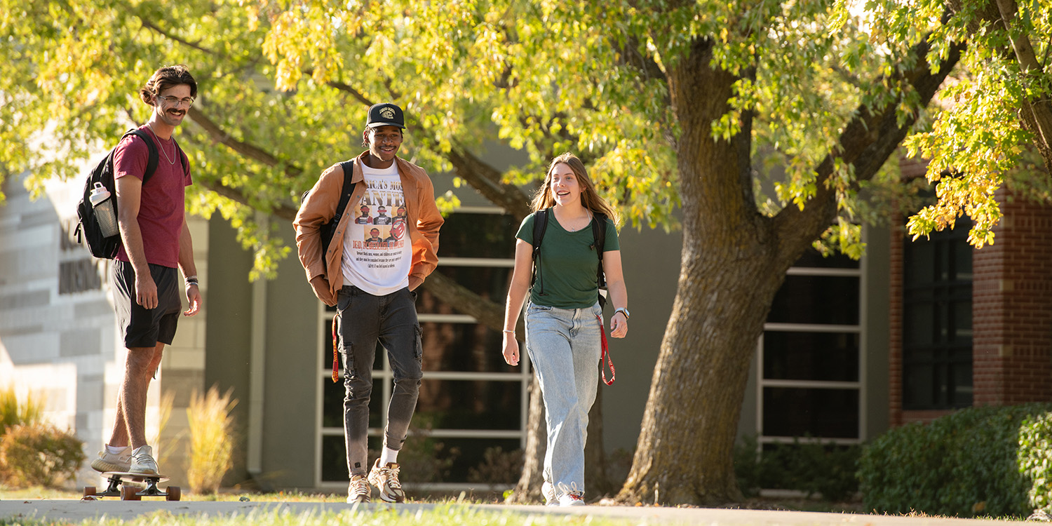 Three students walk together on campus.