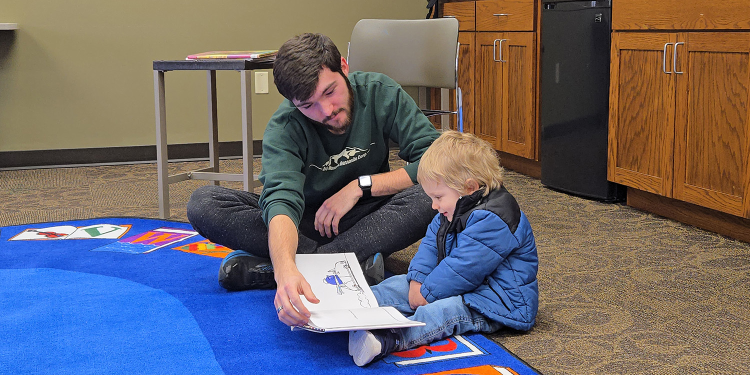 photo - Devin Miller, disc golf team member, took time to read to one of the community’s youngest members at Hesston Public Library, making reading time that much more special.